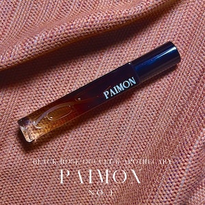 May include: A brown glass bottle with a black cap and the word "PAIMON" printed on the label. The bottle is sitting on a brown fabric surface.