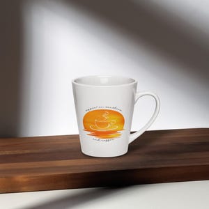 Może przedstawiać: Biały kubek ceramiczny o wysokim, smukłym kształcie i zakrzywionym uchwycie. Kubek przedstawia grafikę zachodu słońca z filiżanką kawy i tekstem "sippin' on sunshine and coffee".