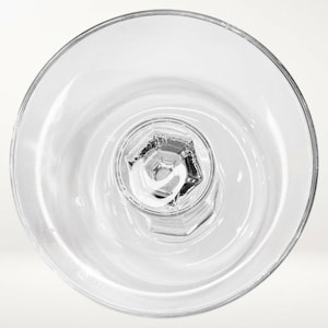 May include: A clear glass goblet viewed from directly above, featuring a wide circular rim and a central stem with a hexagonal base design. The transparent material allows for a clear view of the faceted structure at the bottom of the bowl.