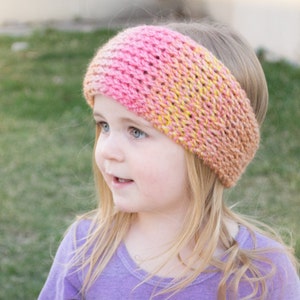 May include: A pink and yellow crocheted headband with a textured stitch pattern. The headband is worn by a young girl with blonde hair.