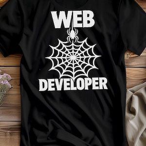 Puede incluir: Camiseta negra con un diseño blanco de telaraña y las palabras "WEB DEVELOPER". La telaraña tiene una araña en la parte superior. La camiseta está hecha de un material suave.