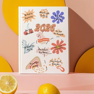Puede incluir: Una agenda blanca de 2026 con ilustraciones coloridas y frases motivadoras. La portada presenta textos como "Lo mejor está comenzando" y "Tu regreso comienza ahora". Dos limones y un limón cortado por la mitad en primer plano.