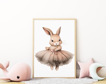 May include: A framed watercolor print of a bunny wearing a pink tutu. The bunny has long ears and a sweet expression. The tutu is adorned with white polka dots. The print is displayed on a white wall with decorative pillows and a plush whale.