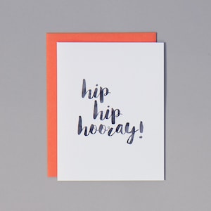 May include: A white card with a coral pink envelope. The card has the words "hip hip hooray!" written in black calligraphy.