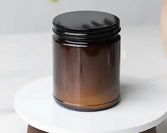May include: A brown glass jar with a black lid. The jar is cylindrical and sits on a small white, round table with three wooden legs. The jar appears to be empty.