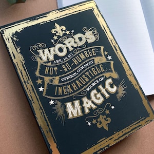 May include: A black notebook with a gold foil design. The cover features the text "Words are, in my not-so-humble opinion, our most inexhaustible source of magic".