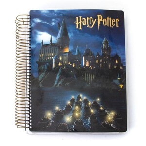 May include: A spiral-bound notebook featuring a nighttime scene of Hogwarts Castle from the Harry Potter series. The cover displays the title "Harry Potter" in gold lettering, with boats on the water below the castle.