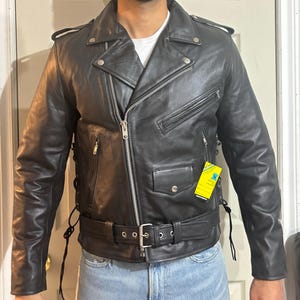 May include: A black leather motorcycle jacket with a zipper closure, a belt, and a yellow tag that says "Genuine Leather".