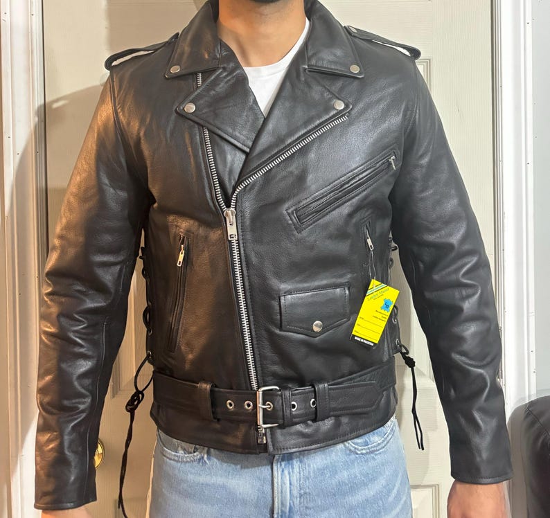 May include: A black leather motorcycle jacket with a zipper closure, a belt, and a yellow tag that says "Genuine Leather".