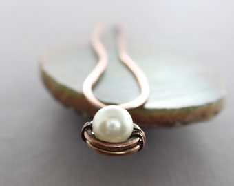 May include: A copper wire hair pin with a white pearl wrapped in the centre.
