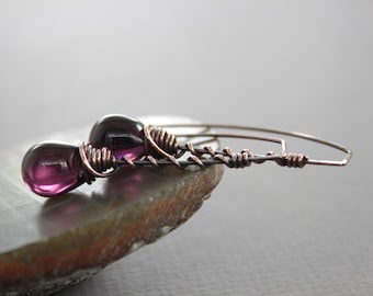 May include: A pair of dangle earrings with purple glass beads and copper wire.