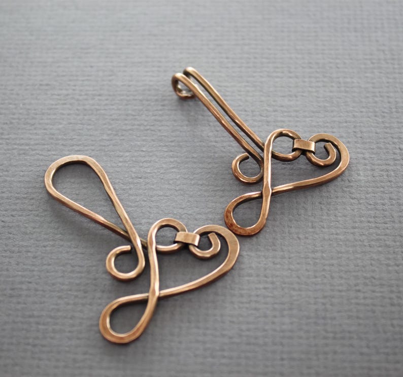 May include: Two copper wire heart-shaped charms with a loop at the top for attaching to jewelry or other crafts.