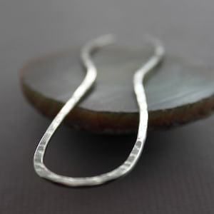 May include: A silver hammered metal hair clip in the shape of a figure eight.