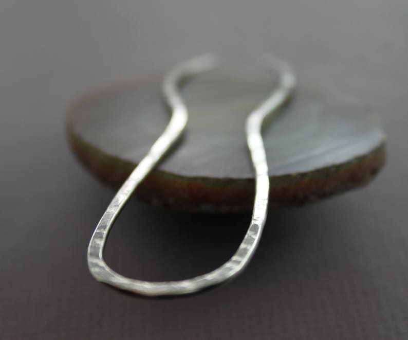 May include: A silver hammered metal hair clip in the shape of a figure eight.