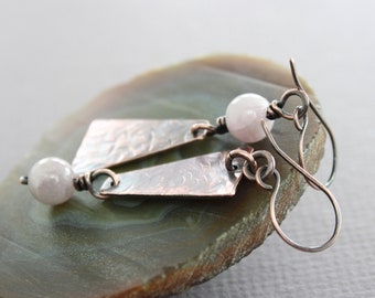 May include: A pair of copper earrings with a hammered finish and a pale pink stone dangle. The earrings have a simple wire hook fastening.