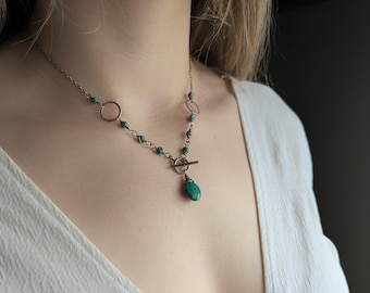 May include: A silver necklace with a turquoise pendant and small turquoise beads. The necklace has a toggle clasp.