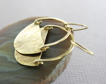 May include: A pair of gold hoop earrings with a hammered, textured, crescent-shaped pendant hanging from each hoop.