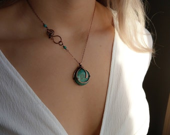 May include: A copper necklace featuring a turquoise stone pendant. The pendant is wrapped in copper wire and has a swirl design. The necklace has a delicate chain and a small turquoise bead accent.