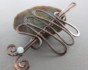 May include: Copper hair comb with a decorative swirl design and a small white gemstone accent.