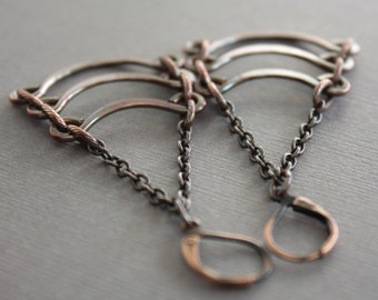 May include: A pair of silver and copper earrings with a curved, layered design and a chain link drop.