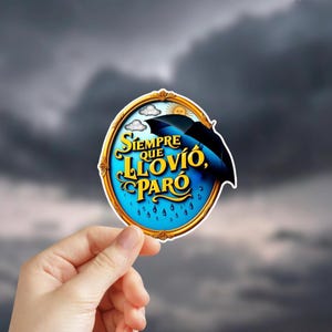 May include: A sticker with a blue and gold design, featuring the text "Siempre que llovió, paró" in a stylized font. The design includes an umbrella, sun, and rain drops against a cloudy sky background.