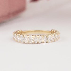 May include: A gold band ring with a row of oval-shaped diamonds set in a pave setting.