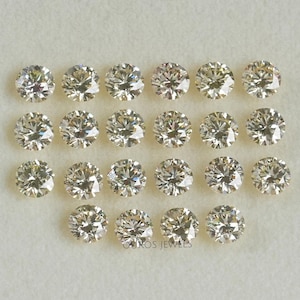May include: A collection of 19 round, clear, faceted, loose diamonds in various sizes. The diamonds are arranged in rows on a white surface.