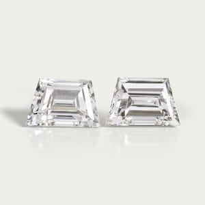 Peut inclure: Deux diamants taillés en trapèze, incolores et transparents, présentant des facettes en escalier. Ces pierres précieuses ont une base large et un sommet plus étroit, offrant une grande clarté et une brillance aux bords géométriques nets.