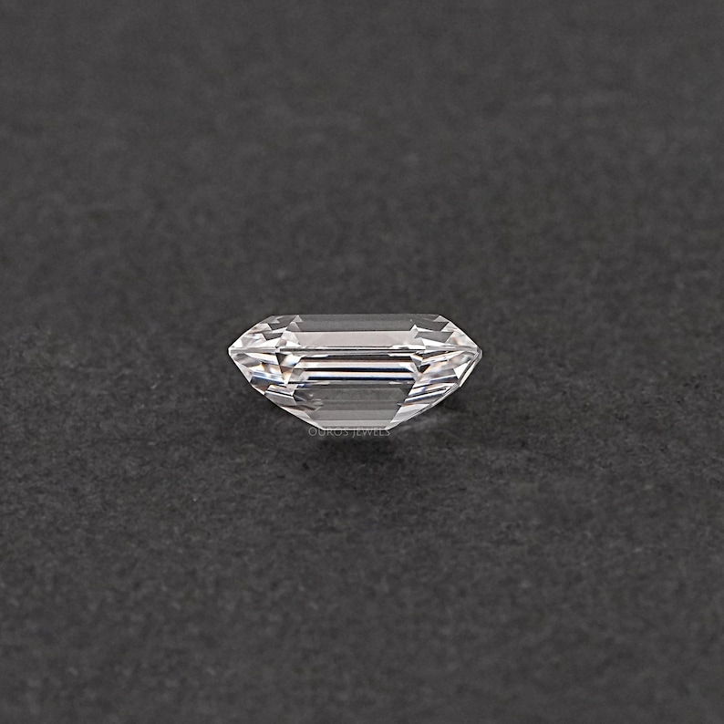 May include: A clear, rectangular emerald cut gemstone with a slight shimmer.