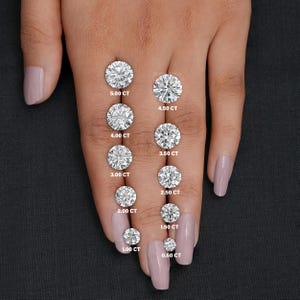 May include: A close-up of a hand displaying ten round diamonds of varying sizes, with carat weight labels ranging from 0.50 CT to 5.00 CT.