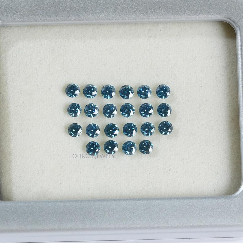 May include: A collection of 20 round, blue gemstones displayed in a white tray. The gemstones are arranged in a rectangular shape with the text "OUROS JEWELS" printed below.