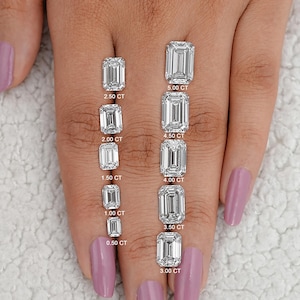 May include: A hand model wearing a clear nail polish displays a size comparison of ten emerald cut diamonds. The diamonds are arranged in a row from smallest to largest, with the carat weight of each diamond labeled below it. The diamonds range in size from 0.50 carats to 5.00 carats.