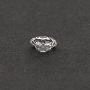 May include: A clear, faceted diamond with a brilliant cut, resting on a dark gray surface. The diamond's facets reflect light, creating a sparkling effect. The image is a close-up, showcasing the clarity and brilliance of the gemstone.