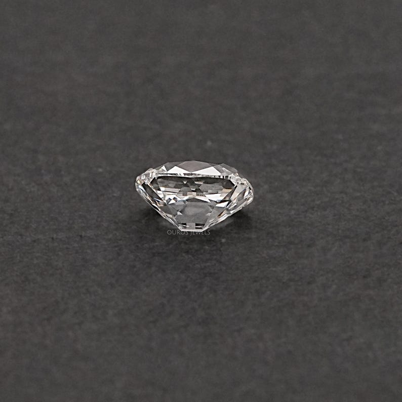 May include: A clear, faceted diamond with a brilliant cut, resting on a dark gray surface. The diamond's facets reflect light, creating a sparkling effect. The image is a close-up, showcasing the clarity and brilliance of the gemstone.