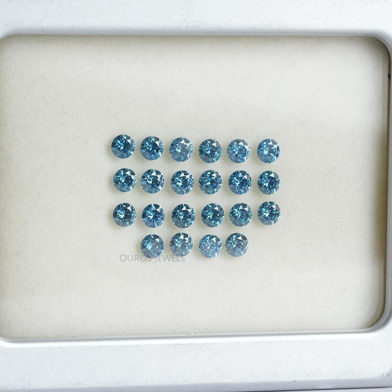 May include: A collection of 20 round, blue gemstones arranged in rows on a white surface. The gemstones are all the same size and shape, and they have a slightly iridescent sheen.