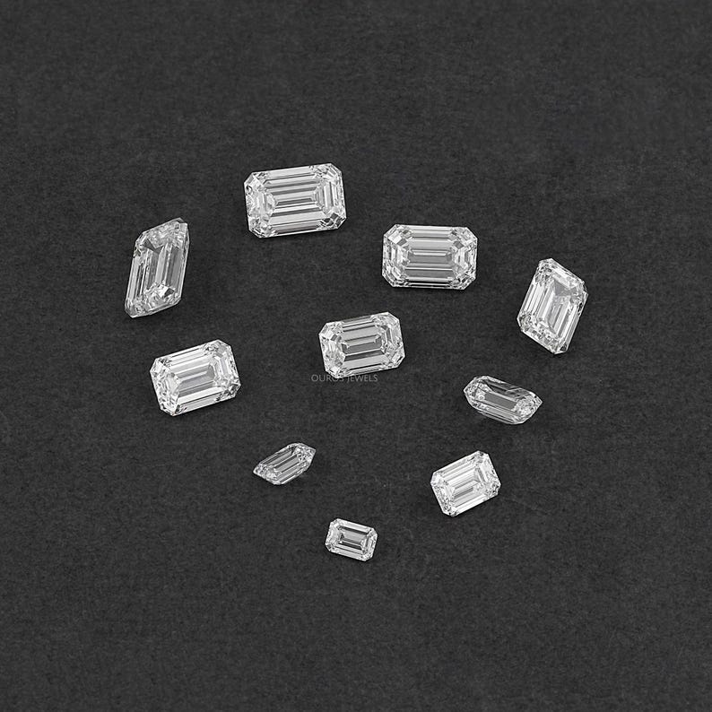May include: Assortment of emerald cut diamonds of various sizes on a black background.