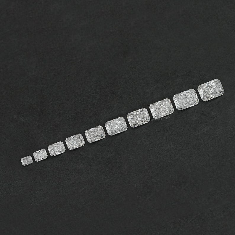 Puede incluir: Una fila de diez piedras preciosas rectangulares, facetadas y transparentes, de diferentes tama&ntilde;os, dispuestas de la m&aacute;s peque&ntilde;a a la m&aacute;s grande sobre una superficie negra.