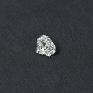 May include: A loose, colorless, pentagonal-shaped diamond with a brilliant-cut facet pattern. The gemstone features sharp, angular edges and a clear, reflective surface. The text OUROS JEWELS is printed in small, faint letters near the bottom edge.