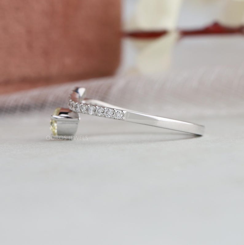Peut inclure: Une bague ouverte argent&eacute;e avec une pierre pr&eacute;cieuse jaune p&acirc;le sertie dans un chaton rectangulaire et un anneau orn&eacute; d'une rang&eacute;e de petites pierres pav&eacute;es transparentes. L'anneau en m&eacute;tal est lisse et poli, avec le texte OUROS JEWELS visible.