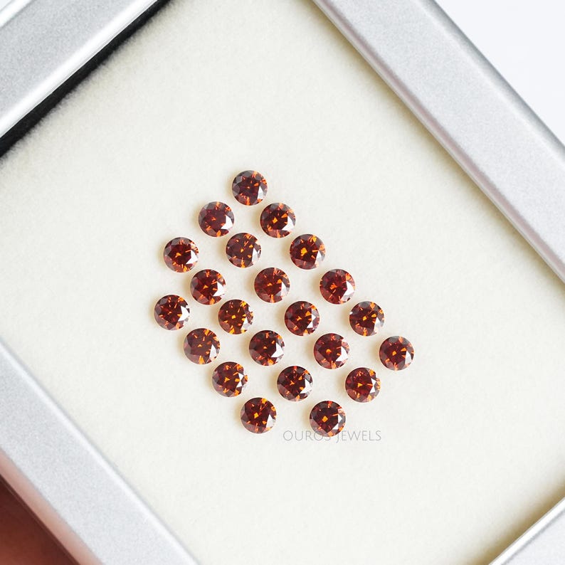Puede incluir: Una colecci&oacute;n de 20 diamantes marrones redondos y facetados en una caja blanca. Los diamantes est&aacute;n dispuestos en un patr&oacute;n escalonado.