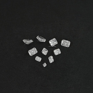 Puede incluir: Surtido de piedras preciosas rectangulares facetadas transparentes sobre un fondo negro.
