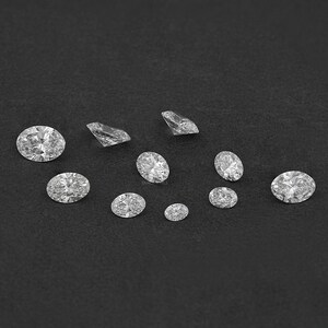 Pu&ograve; includere: Una collezione di diamanti rotondi e ovali di varie dimensioni su uno sfondo nero.