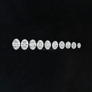 May include: A set of 10 oval-shaped, clear gemstones of varying sizes, arranged in a row from largest to smallest on a black background.