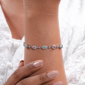 Puede incluir: Una pulsera de plata con una fila de piedras preciosas de colores engastadas en un halo de diamantes m&aacute;s peque&ntilde;os. Las piedras preciosas son rosas, azules y verdes.