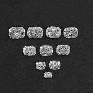 K&ouml;nnte beinhalten: Eine Sammlung von zehn klaren, facettierten, kissenf&ouml;rmigen Diamanten in verschiedenen Gr&ouml;&szlig;en, die in einem dreieckigen Muster auf einem schwarzen Hintergrund angeordnet sind.