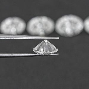 Pu&ograve; includere: Un diamante trasparente, rotondo e sfaccettato, tenuto da una pinza. Il diamante &egrave; tagliato a brillante rotondo.