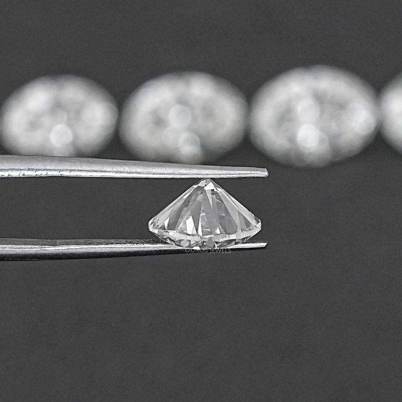 Pu&ograve; includere: Un diamante trasparente, rotondo e sfaccettato, tenuto da una pinza. Il diamante &egrave; tagliato a brillante rotondo.
