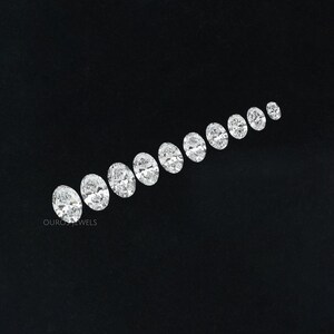 May include: A row of oval-shaped diamonds of varying sizes, arranged from largest to smallest, on a black background. The diamonds are clear and sparkly.