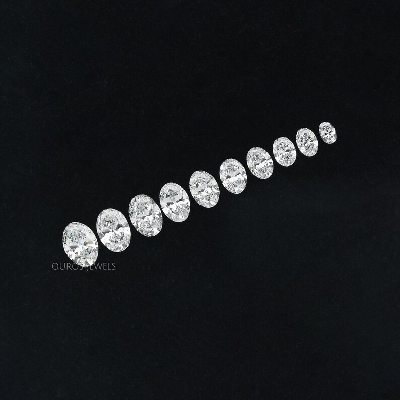 May include: A row of oval-shaped diamonds of varying sizes, arranged from largest to smallest, on a black background. The diamonds are clear and sparkly.