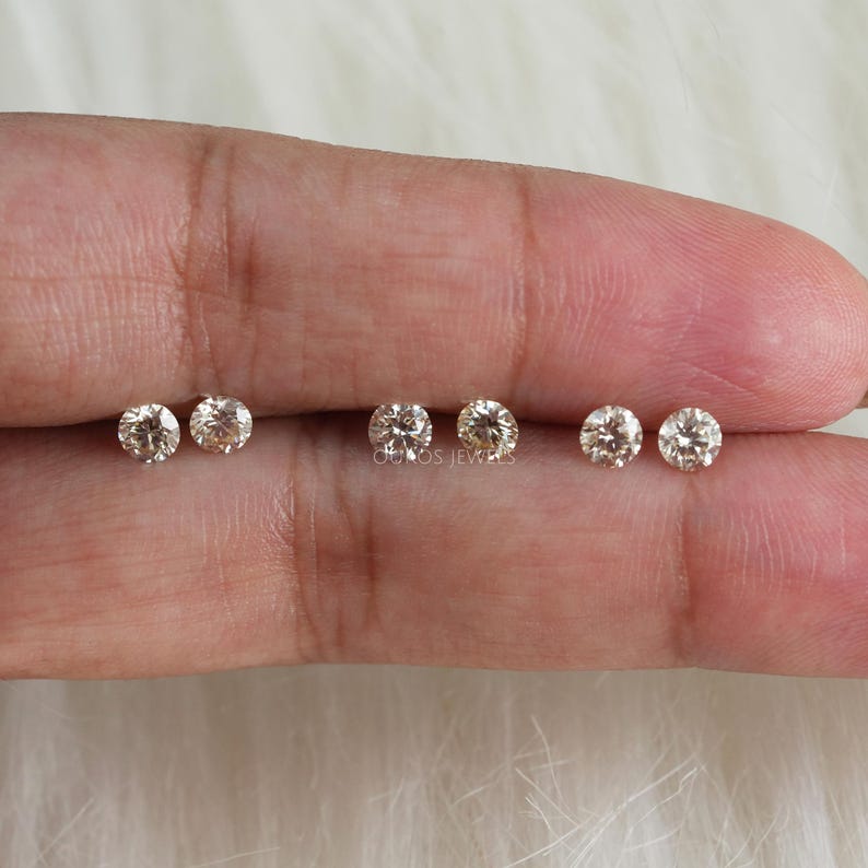 May include: Six round, clear, gemstone earrings in various sizes. The earrings are displayed on a hand.